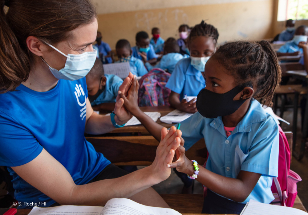 Celine van Till hält während ihrer Reise nach Kambodscha die Hände eines kleinen Mädchens in einem Klassenzimmer.